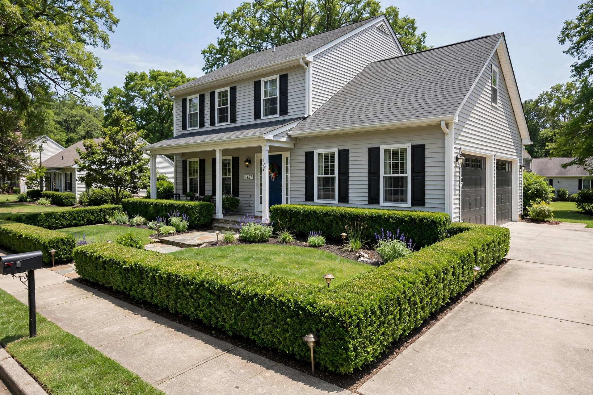 Neatly trimmed boxwood hedge border along the front of a suburban house.